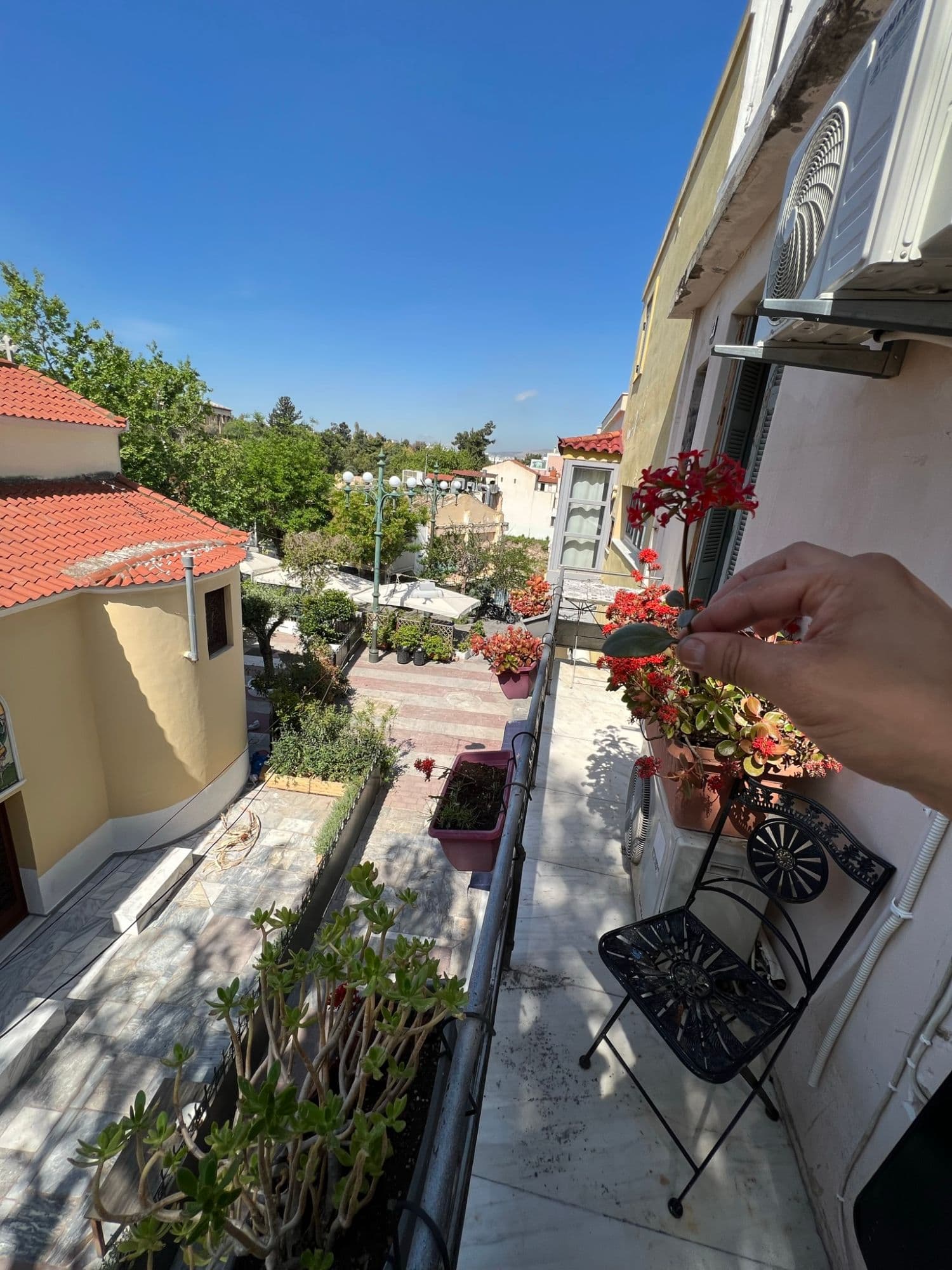 Balcony view over a plaza with a church and flowers in Athens