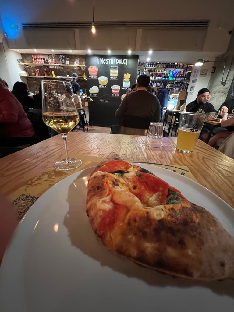A slice of pizza and a glass of wine at a restaurant in Catania