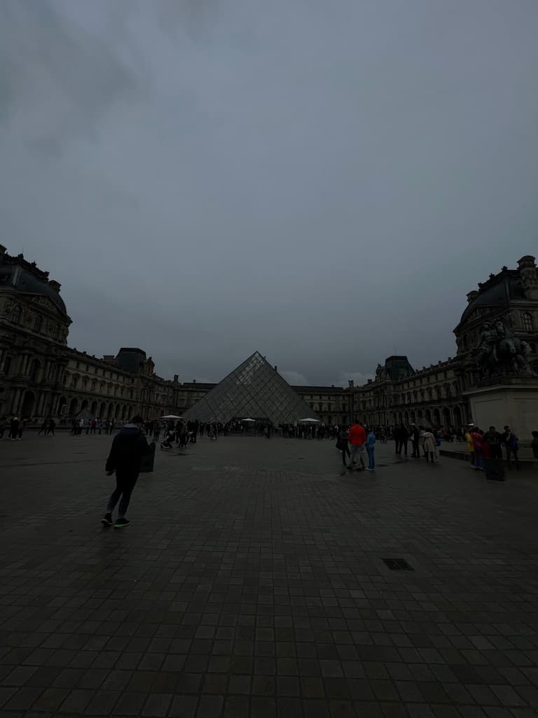 The Louvre pyramid under an overcast sky in Paris